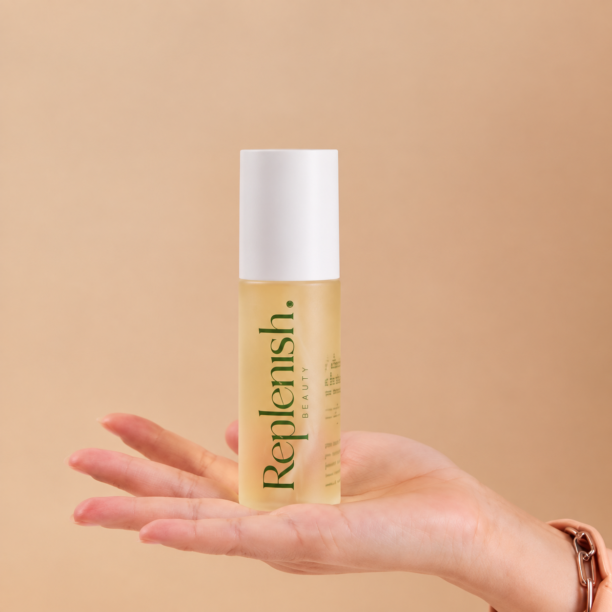 A hand holding Replenish Daily Cleanser against a light peach background