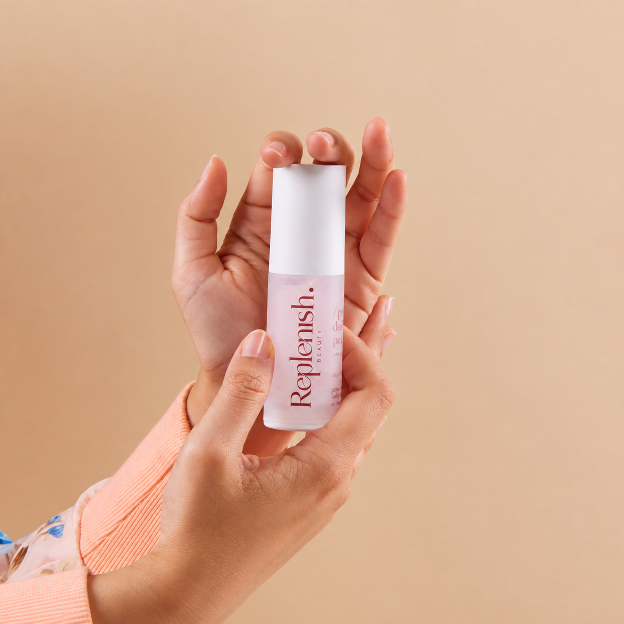 Two hands holding Replenish Prebiotic Skin Peel against a light peach background